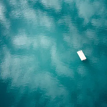 Kärntner Seen Schwimmender Holzsteg auf ruhigem türkisfarbenem See mit Himmelsreflexionen